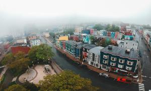 Photo by Erik Mclean - cityscape with bright buildings and roads under sky in mist