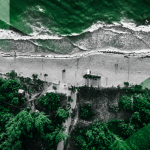 A dramatic aerial view of Jamaica’s coastline, reimagined in Jamaica Homes News’ signature green-and-grey style, highlighting the close relationship between land, development and the sea.