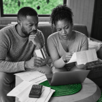 A Jamaican couple carefully reviews household bills and finances, highlighting the growing pressure of everyday housing costs on family budgets.