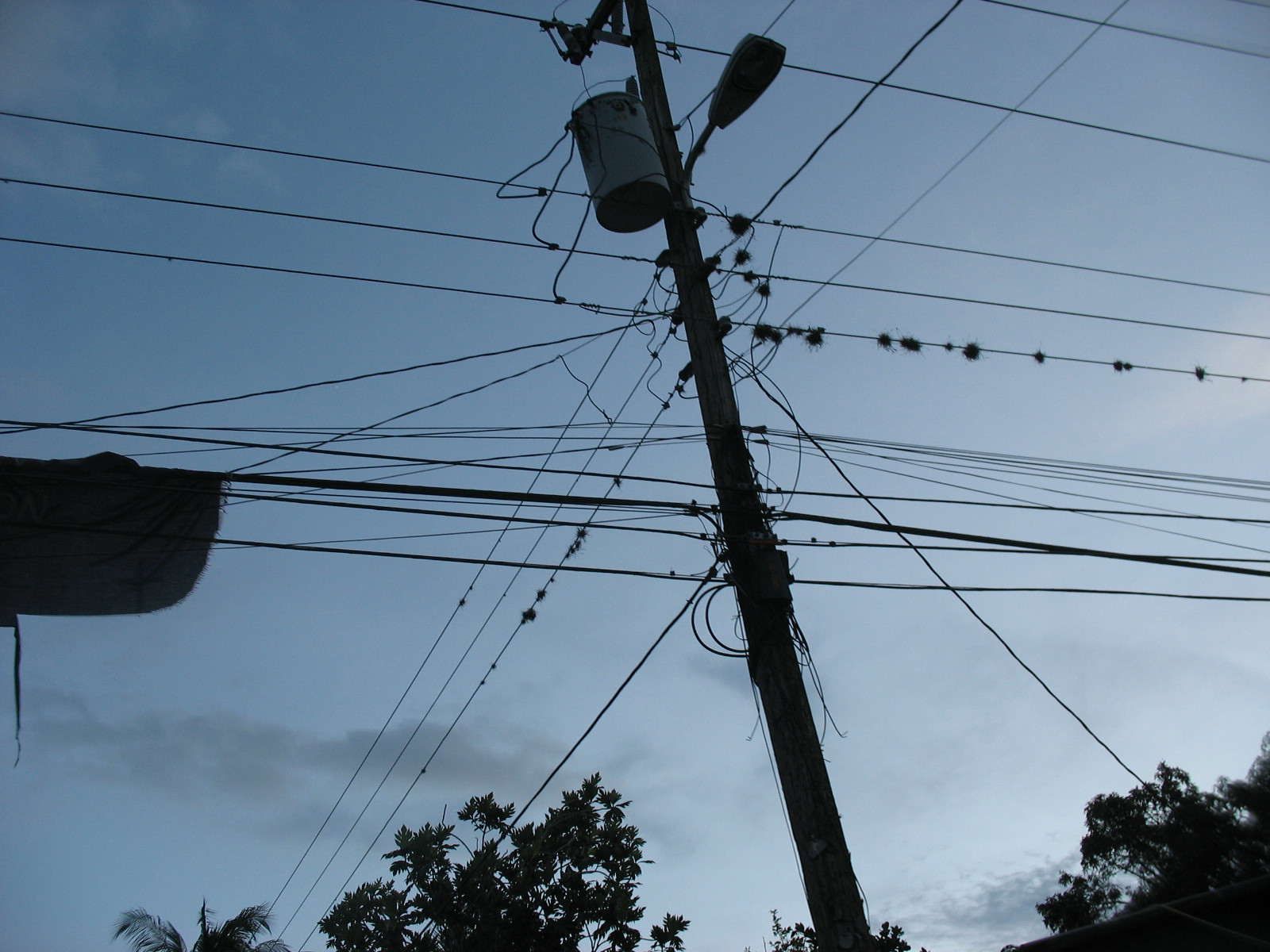 A utility pole carrying a tangle of overhead power and telephone lines in Jamaica
