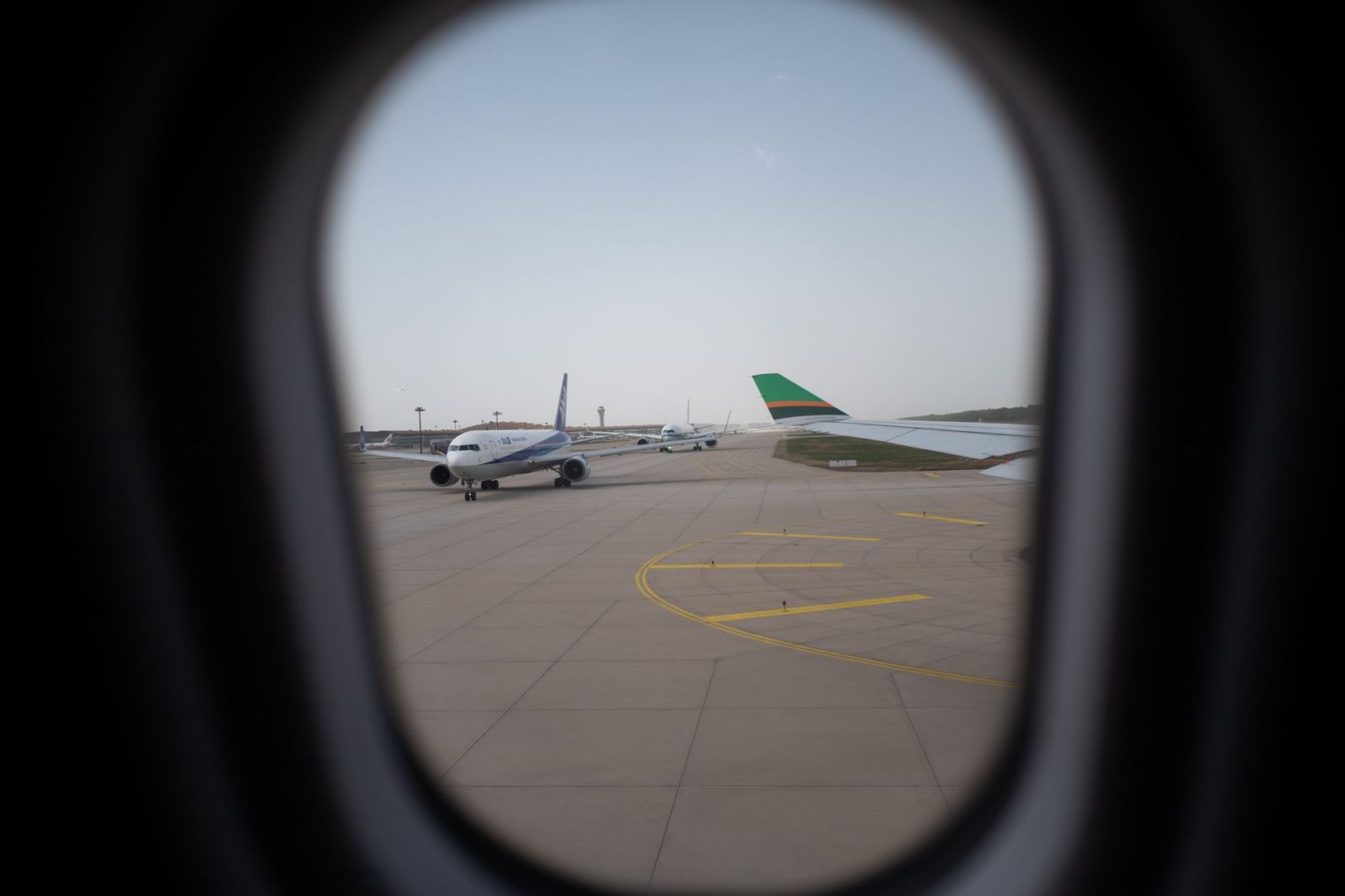 planes on airport runway view through a porthole