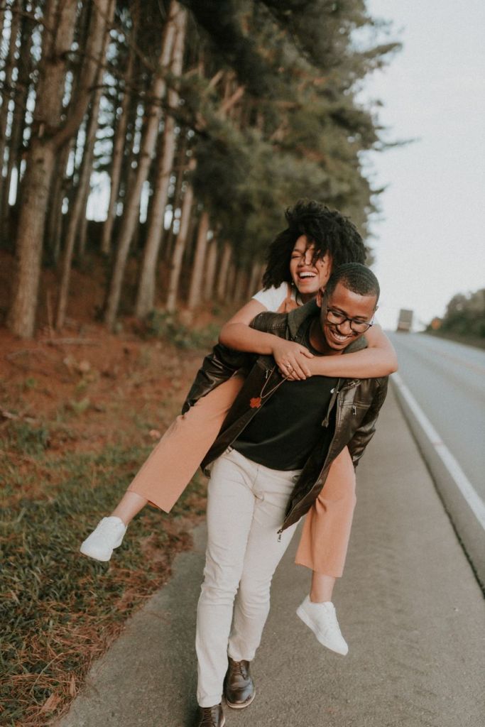 smiling woman sitting on man on road