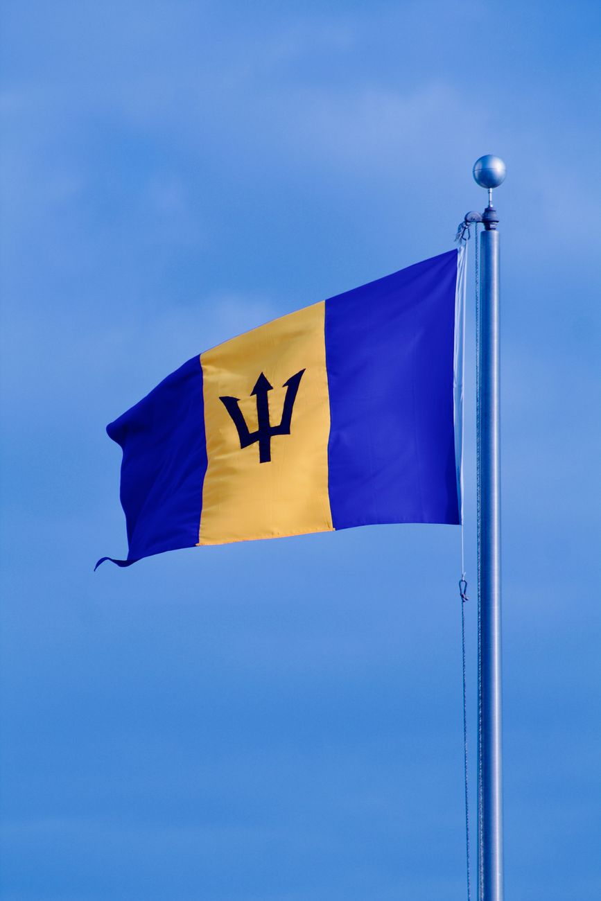 barbados national flag waving in blue sky