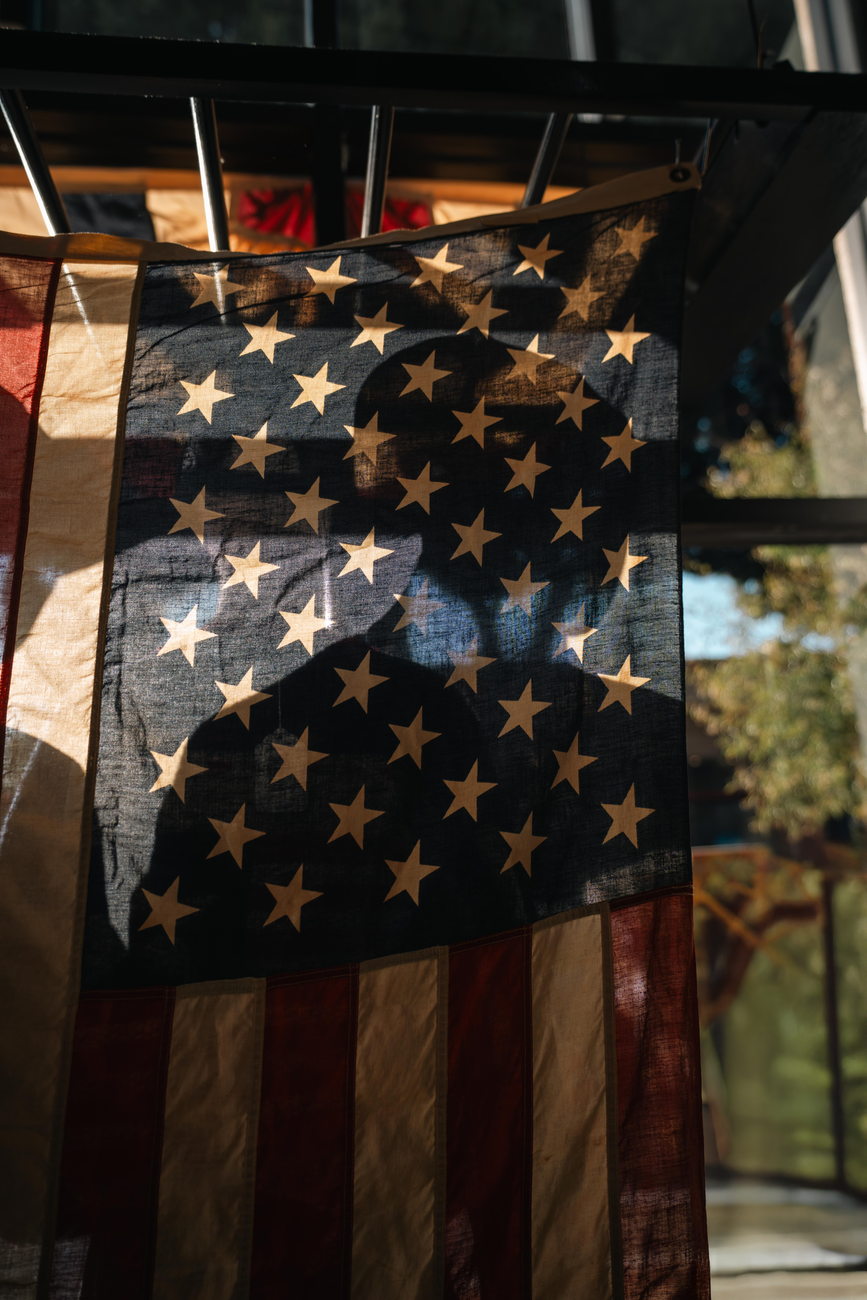 silhouette behind waving american flag - Photo by James Collington
