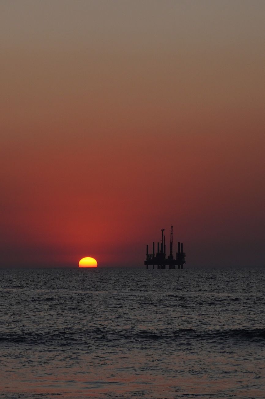 sunset silhouette of offshore oil rig - Photo by Chinu