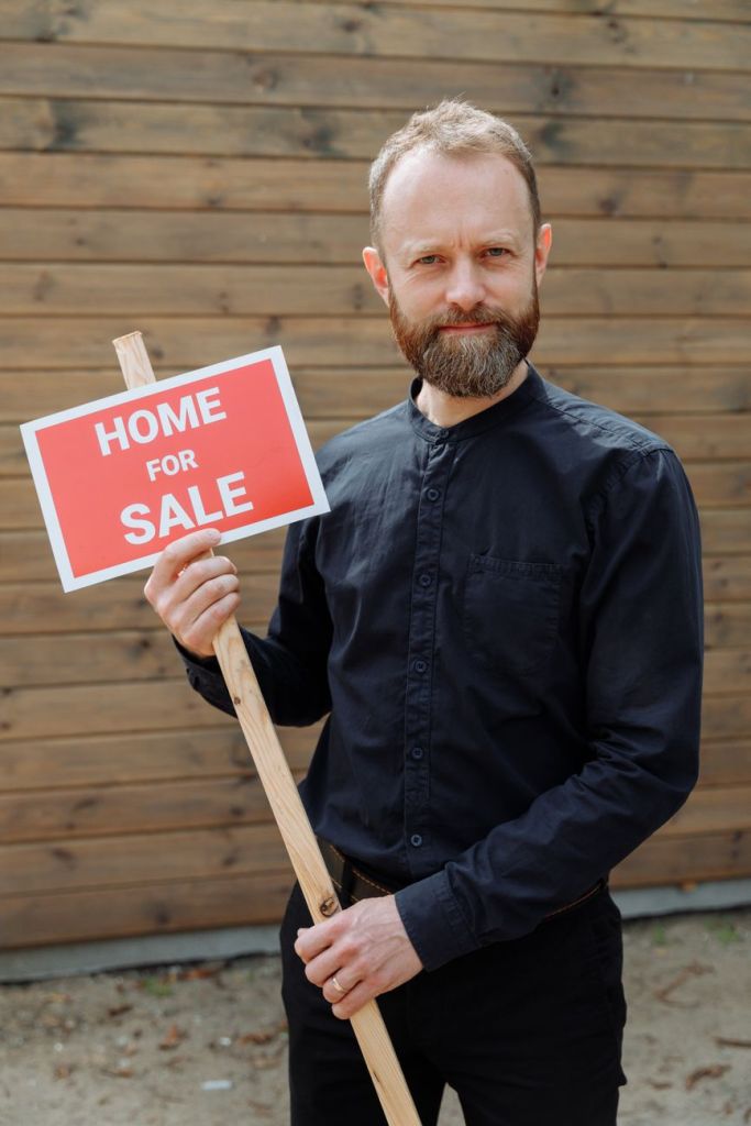 Britain’s Landlords Are Borrowing Again—but the Boom Is Not Back man in black long sleeves holding a signage - Photo by Thirdman