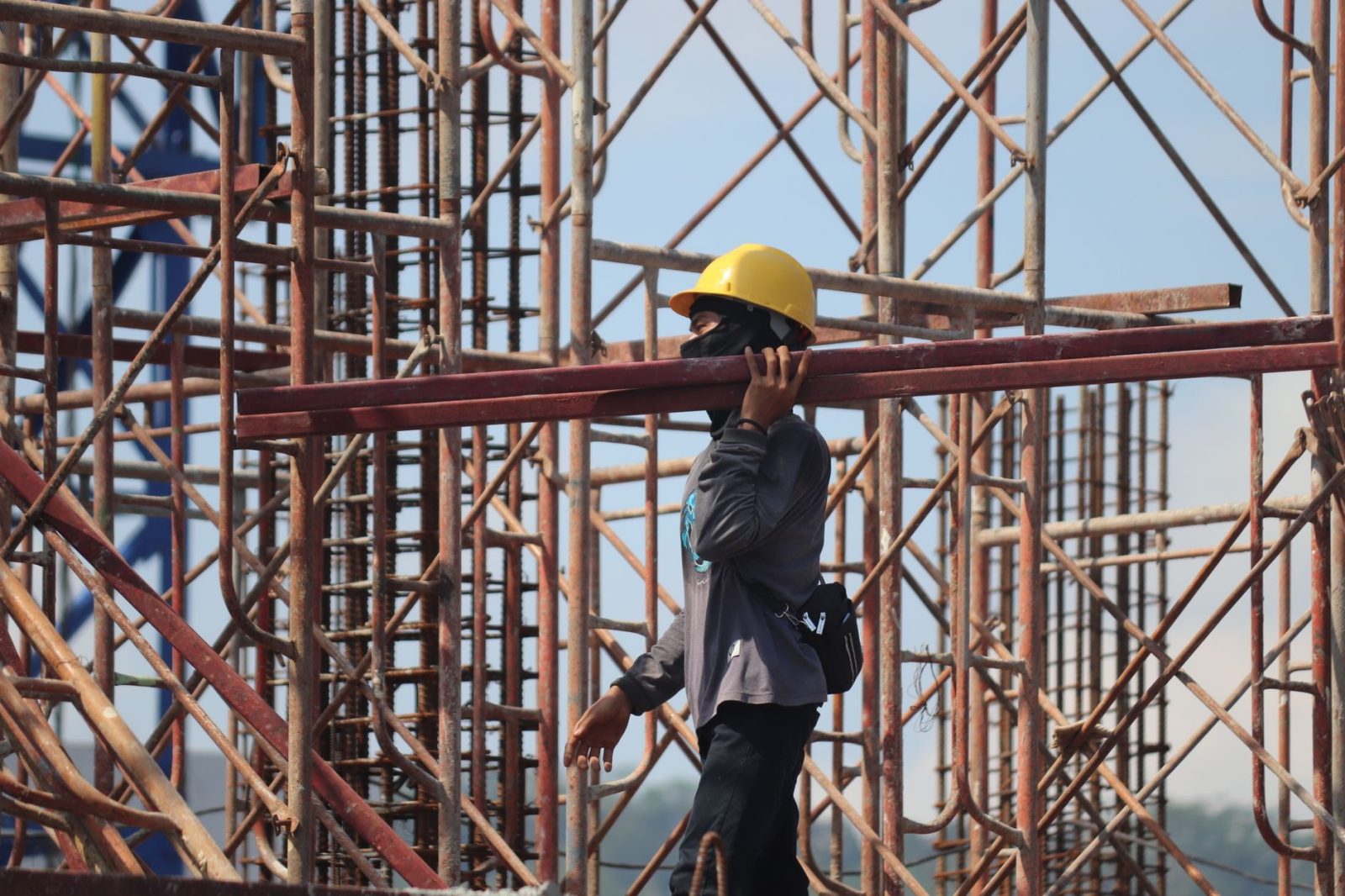 man in yellow helmet carrying steels
