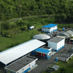 Aerial photograph of a WASCO water treatment facility in Saint Lucia, with blue and white buildings and treatment tanks